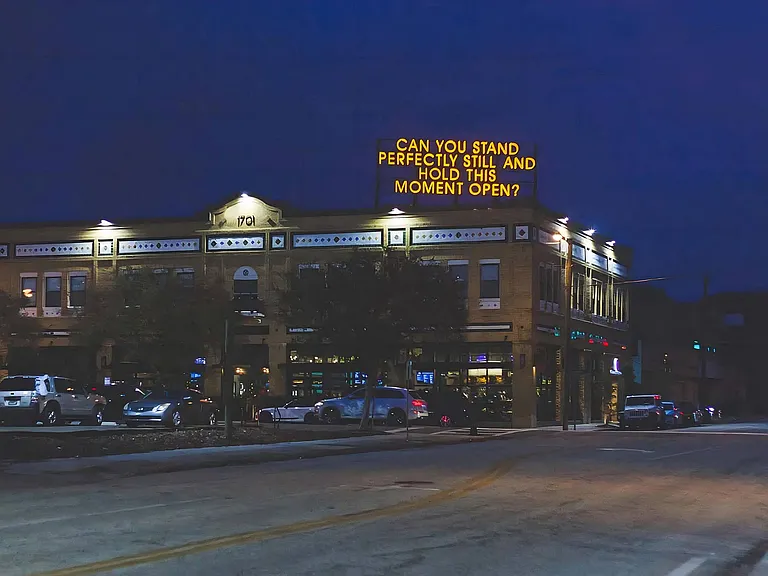 Evening View of Brick Building with Artistic Rooftop Message and Street Lighting