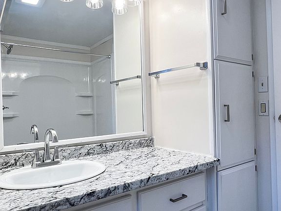 Renovated bathroom with oversize mirror, new fixtures, vanity, and shower. Plenty of storage within and on both sides of the vanity.