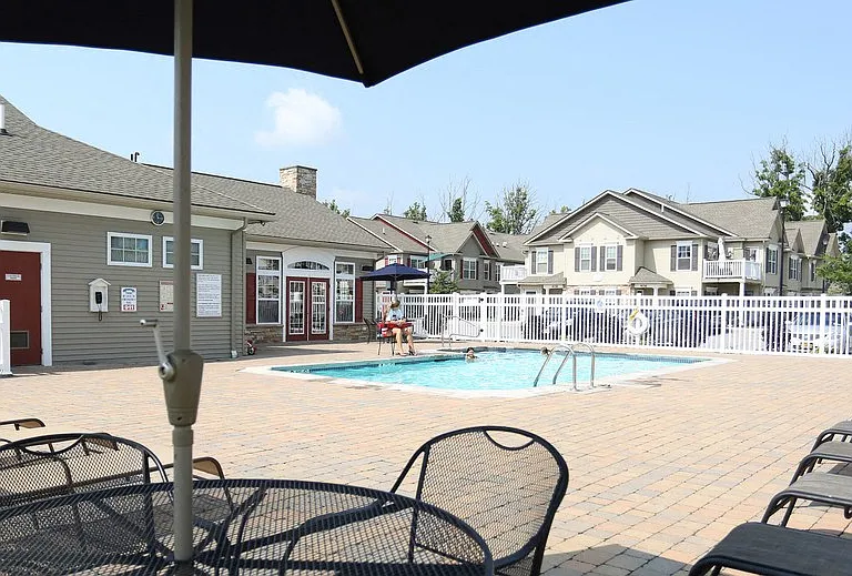 Outdoor swimming pool with large pool deck, tables, and chaise longues