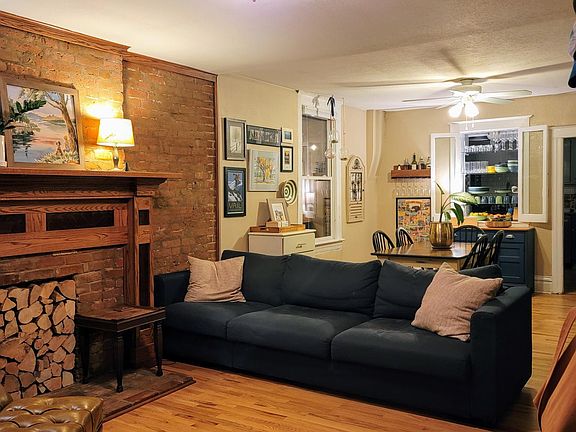 Photo taken from front door; Livingroom features exposed brick, hardwood floors and open into dining room.
