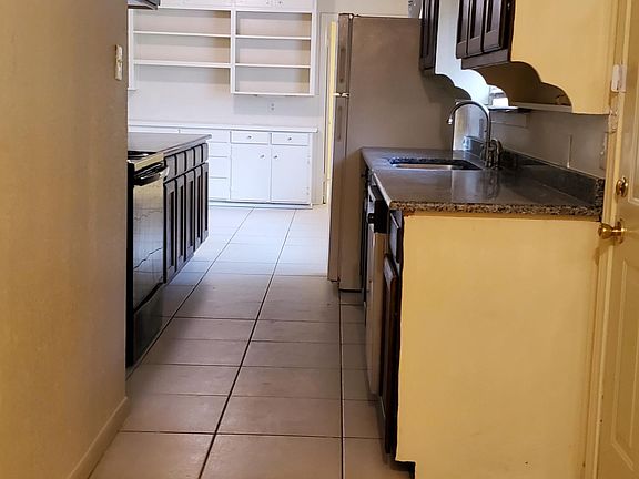Kitchen viewed from the laundry room. Dining room at the far end with builtin shelves and cabinet