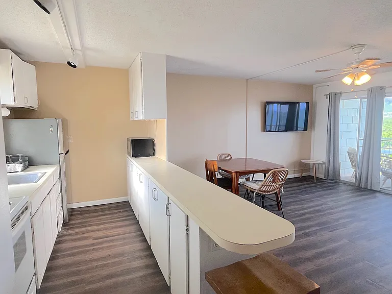 Full-size range with electric stove top, refrigerator and microwave, with extra storage in the kitchen peninsula.