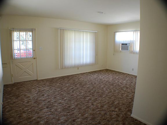 Front door living room entry seen from the dining area. A new window air conditioner is in the corner.