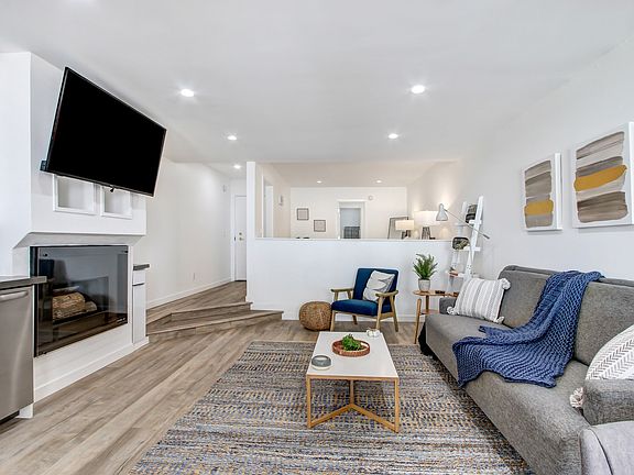 Living room with wood inspired floors, cozy fireplace, recessed lighting, furnished unit