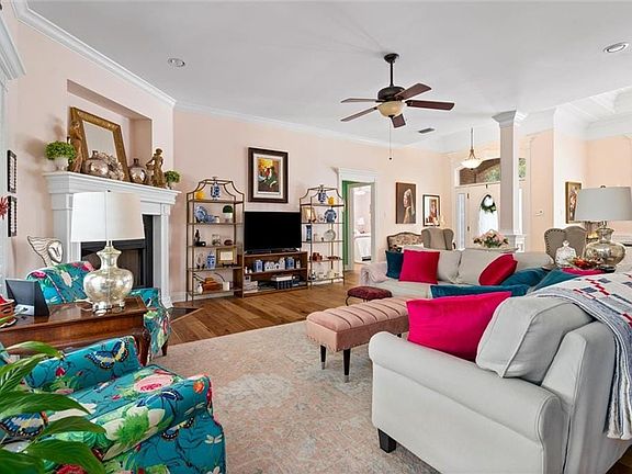 Living area featuring a fireplace, crown molding, wood finished floors, and a ceiling fan