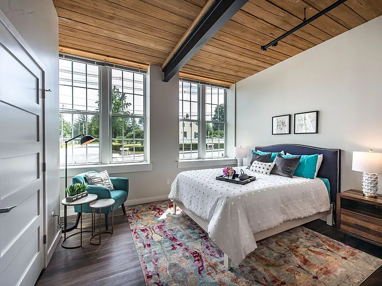 Spacious Bedroom With Large Windows, Exposed Beam Ceiling And Wood Plank Floors.