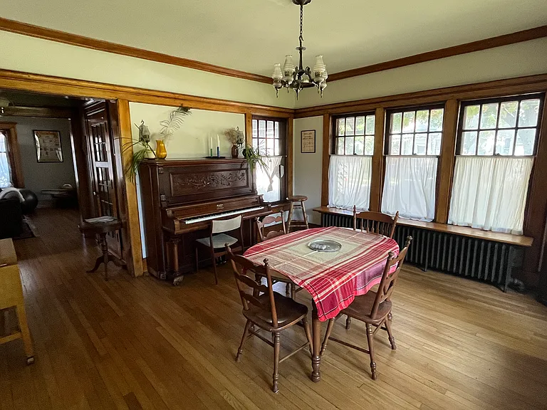 Sun-filled dining room with antique upright piano and antique radio