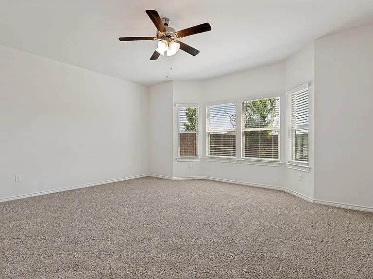Spacious room featuring neutral carpeting, light-toned walls, and a bay window with multiple panes