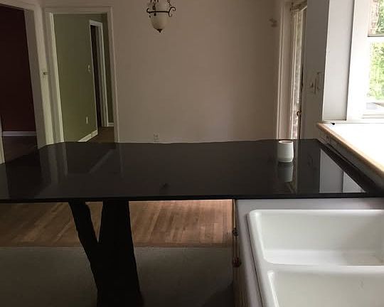 View from kitchen over granite countertop and dining area