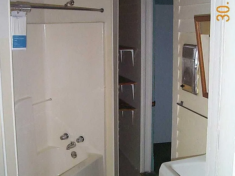 Bathroom coming in from the hall, with storage space for linens and toiletries at the end of the shower/bath unit .