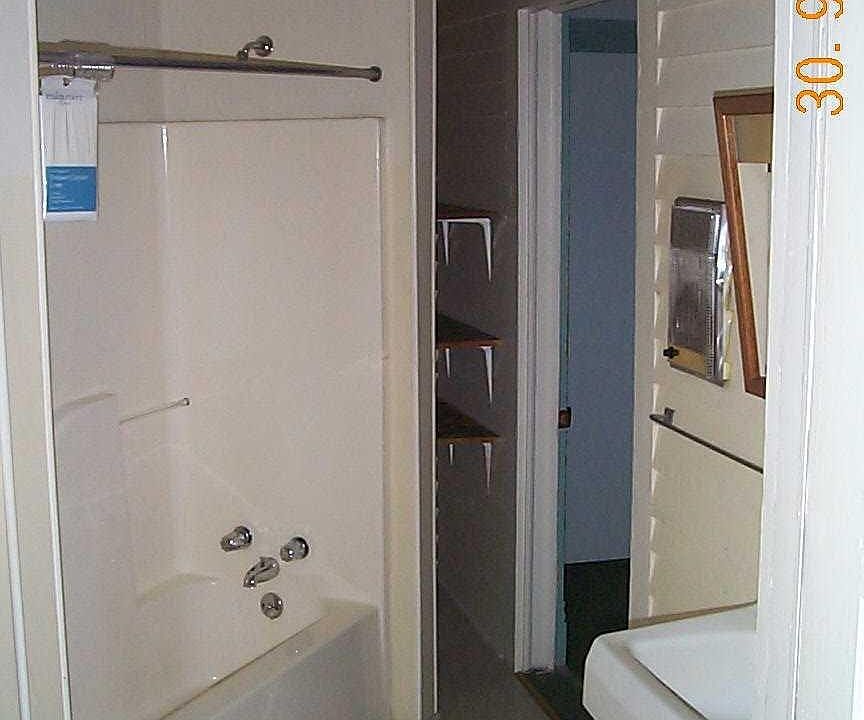 Bathroom coming in from the hall, with storage space for linens and toiletries at the end of the shower/bath unit .