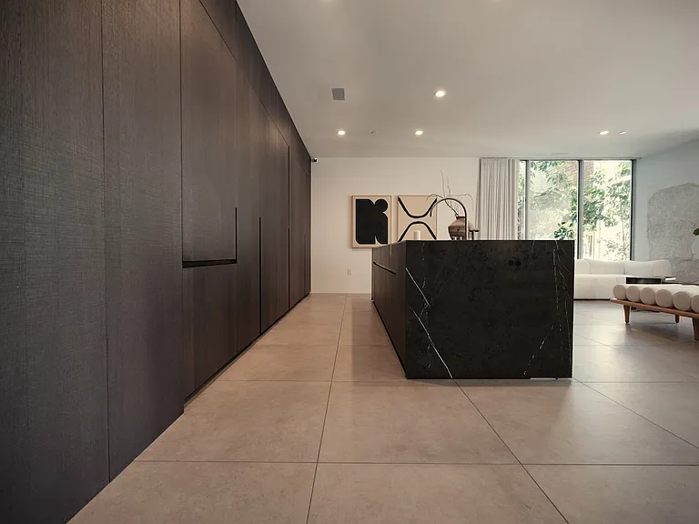 Sleek Kitchen Design with Integrated Storage _ This sophisticated kitchen features a striking black stone island and floor-to-ceiling custom cabinetry with seamless, handle-free panels.