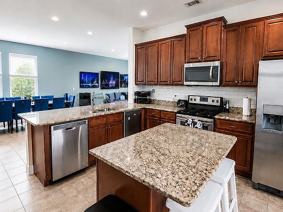Open-concept kitchen with granite counters, ample cabinetry, stainless appliances, and a large island beside the dining area.