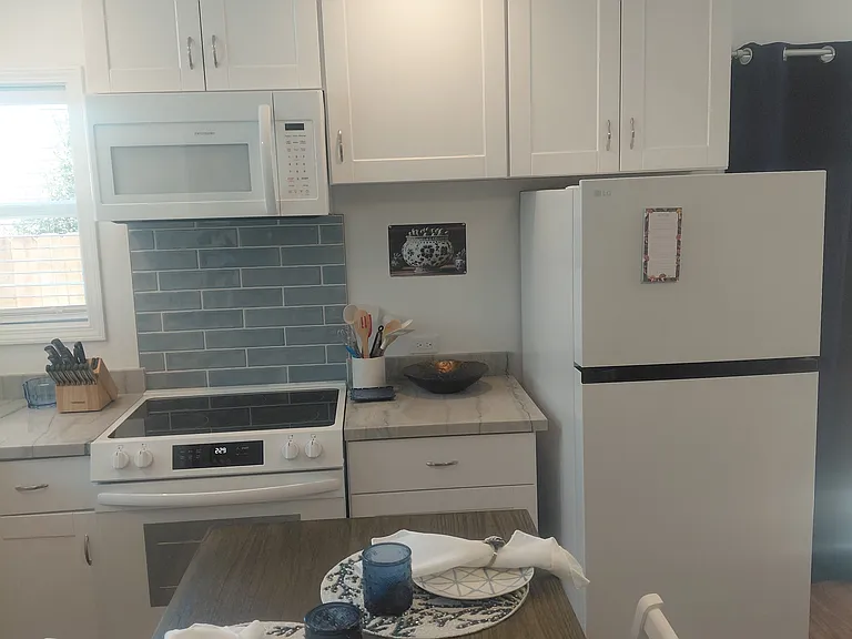 White Appliances: Stove, Oven, Kitchen Table, Refrigerator and Microwave, kitchen knife set, plates, silverware and other kitchen essentials.