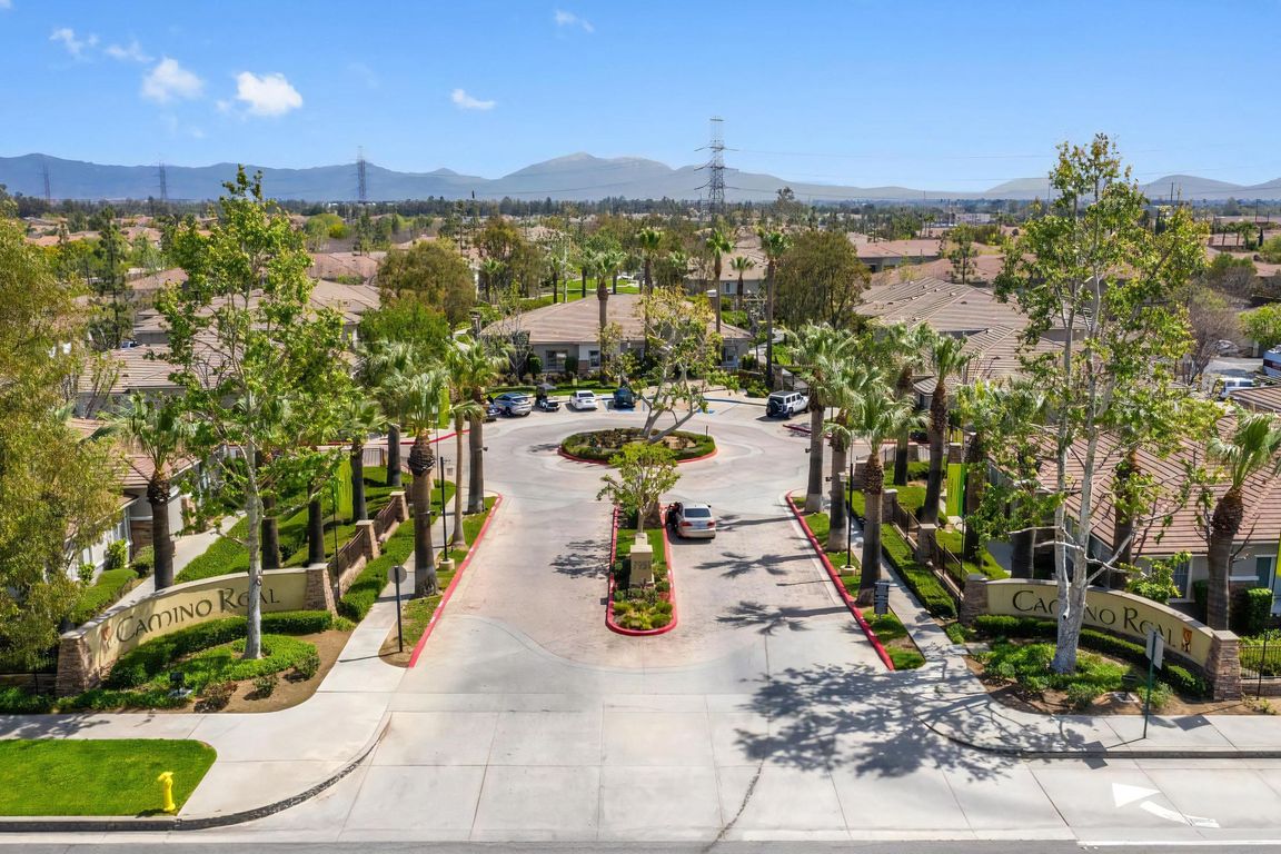 Gated Entrance to Camino Real Apartment Community with Palm-Lined Drive