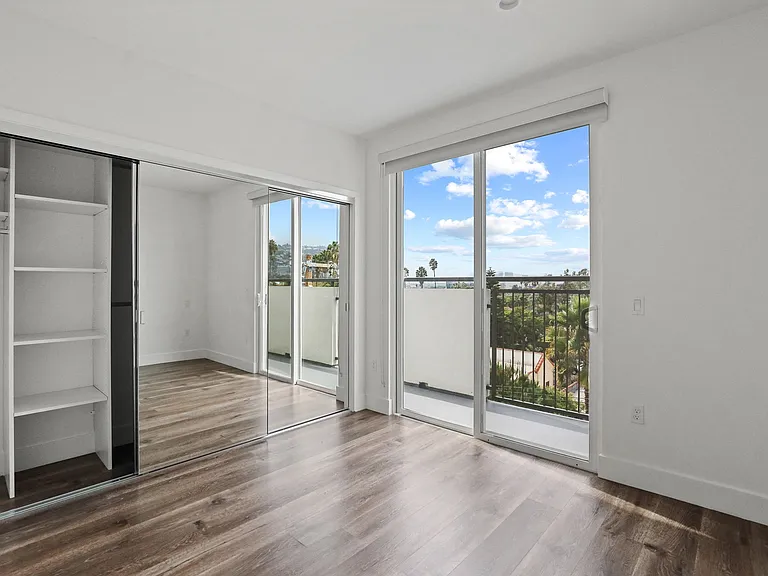 Bedroom with Large-Size Mirrored Closet with Shelving, Vinyl Flooring, and Balcony