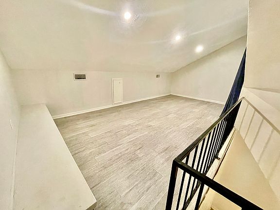 A black wrought-iron spiral staircase leads to a spacious loft, perfect for a bedroom, office, or retreat.