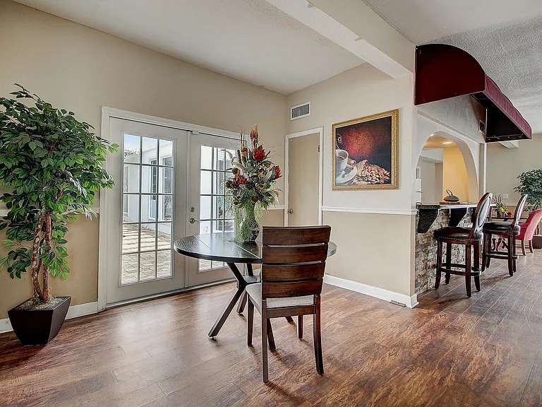 Charming dining area with elegant table setting, warm wood flooring, and natural light streaming through double French doors.