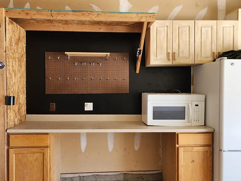 Work bench in Garage with Fridge and microwave.
