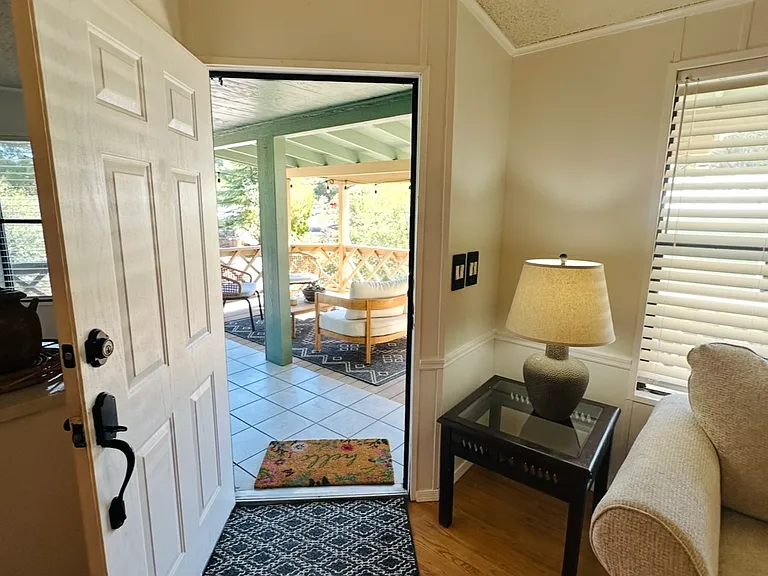 Front door, off porch entrance with furnished living room.