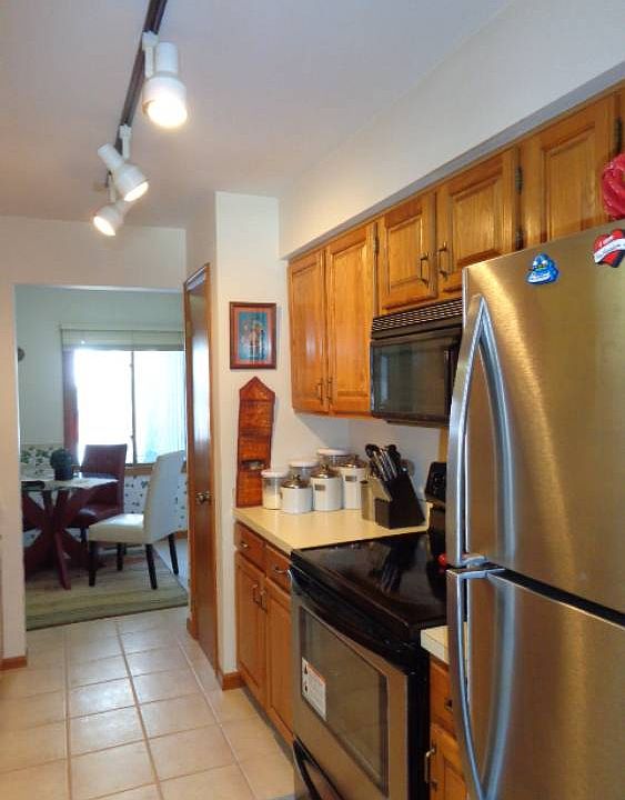 Kitchen with newer stainless steel appliances. Ceramic tile flooring and track lighting.