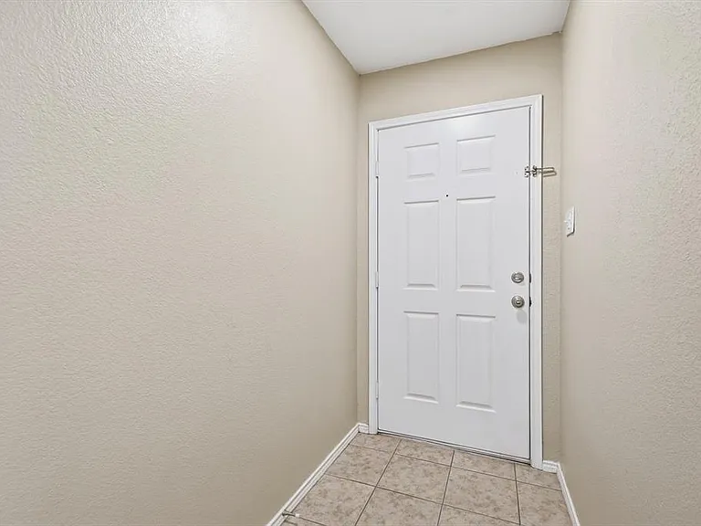 Doorway with tile patterned floors and a textured wall