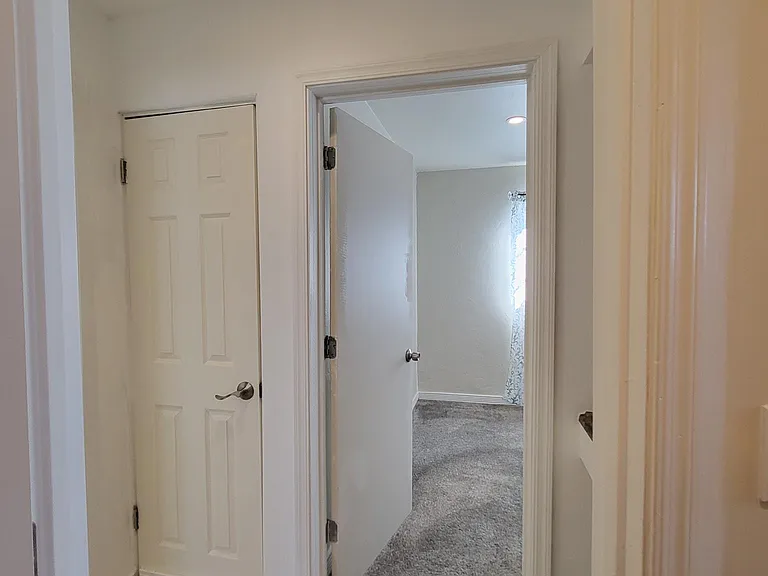 Hall from bathroom leading to closet door and second bedroom