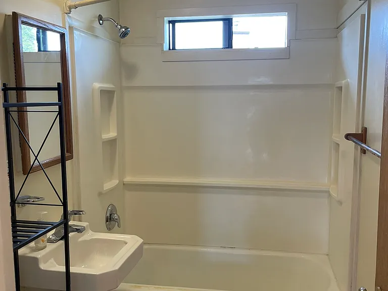 Bright Bathroom with Built-In Shower/Tub and Bathroom Storage Rack For Toiletries, etc