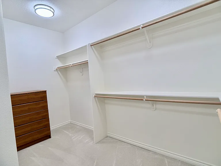 Final section of the expansive walk-in closet, featuring additional custom shelving and hanging space, along with a Danish-built five-drawer dresser.