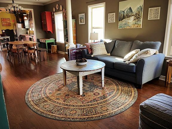 View on front room from front door area with new couch, TV and rugs.