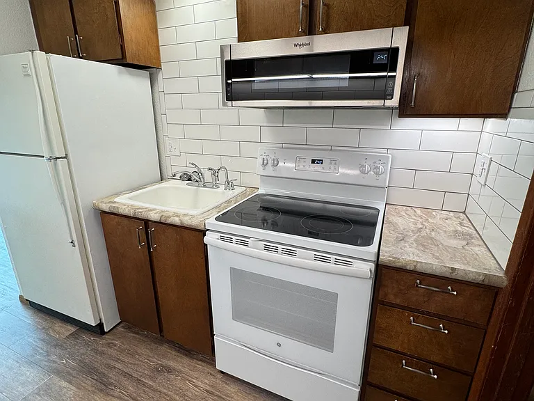 Kitchen with brand new microwave and tile backsplash. New vinyl plank flooring throughout. Unit comes with an Instahot water dispenser, new faucet and garbage disposal.