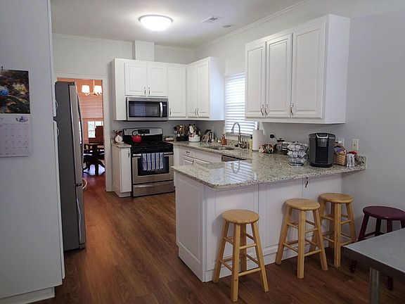 Kitchen with granite counters, counter seating, eat-in area and stainless steel appliances. Natural gas cooking.
