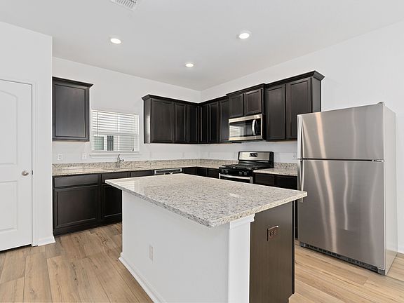 Chef-ready kitchen with a large island, stainless appliances, and granite countertops.