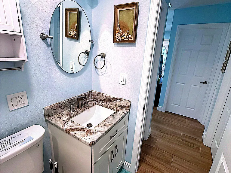Bathroom features a granite-topped vanity with under-sink storage, updated lighting, and tile-style flooring.