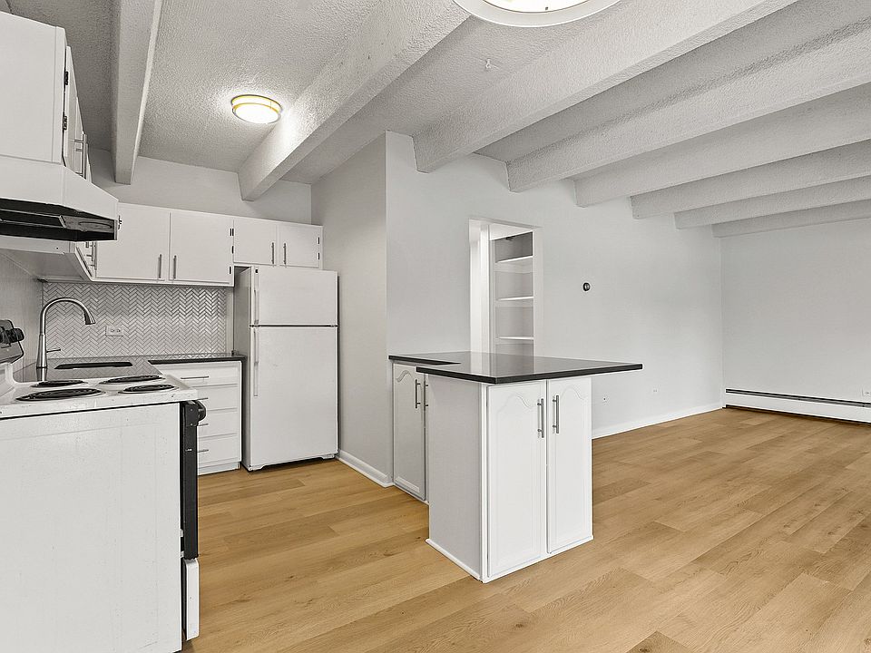 Bright modern kitchen with sleek white cabinetry, elegant backsplash, and open layout with hardwood floors.