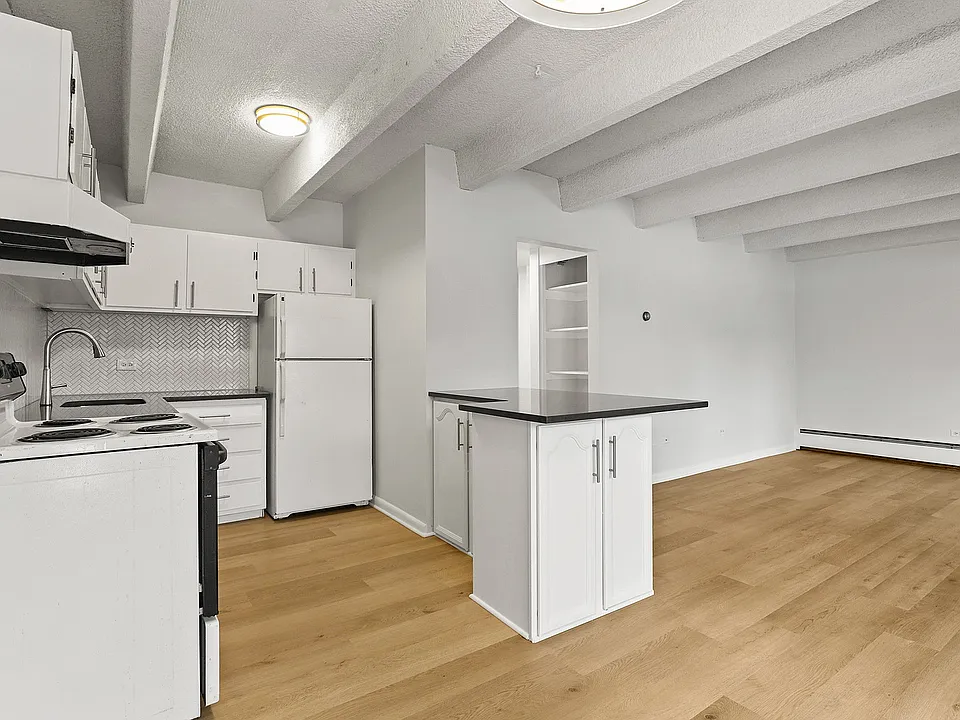 Bright modern kitchen with sleek white cabinetry, elegant backsplash, and open layout with hardwood floors.