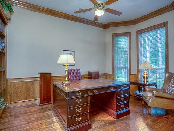 Executive study features french doors, built-in's, stained crown molding and wainscoting, bay window