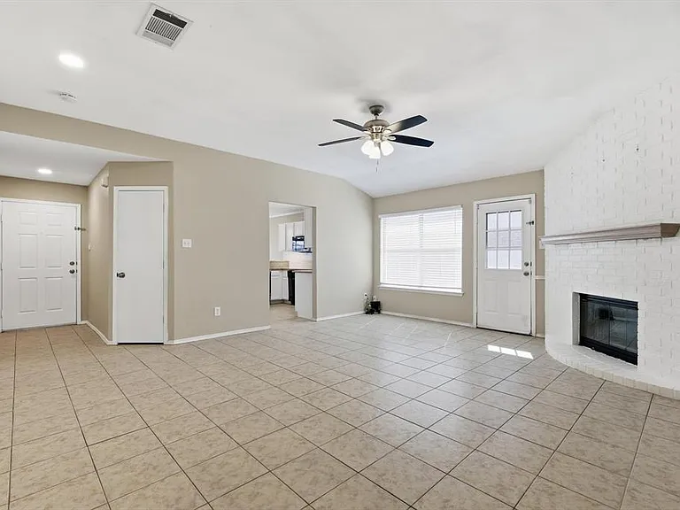 Unfurnished living room featuring ceiling fan, light tile patterned flooring, and a brick fireplace