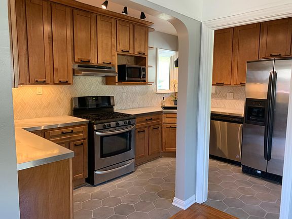 Bright kitchen with slab countertops, full backsplash and stainless appliances