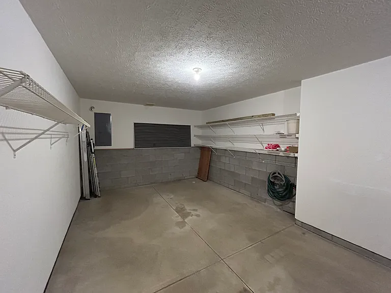 Storage shelves in garage and water hose line.