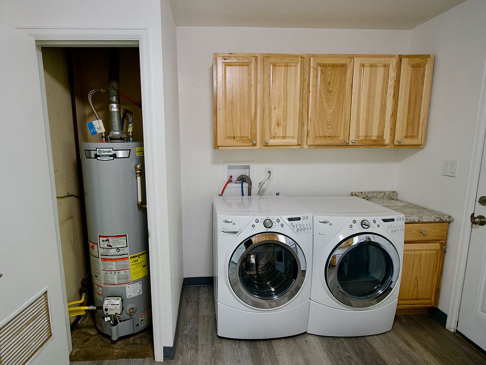 New water heater and front loaded washer and dryer with additional cabinets for laundry