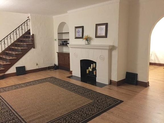 Living room with built-in bookcase (rug included) and gorgeous refinished original hardwood floors.