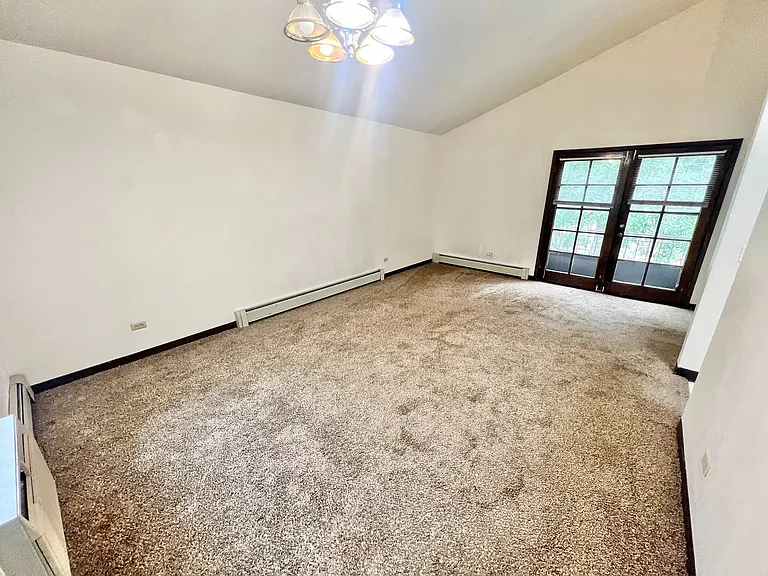 Bright living space with plush carpeting and elegant French doors, offering a cozy and inviting atmosphere.