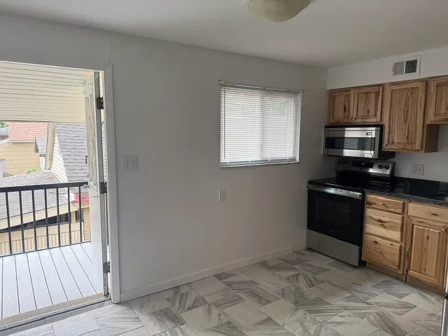 KITCHEN WITH ALL NEW STAINLESS STEEL APPLIANCES AND VIEW OF EXTERIOR UNIT DOOR LEADING TO COVERED PORCH/DECK WITH TREX DECK