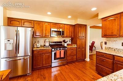 WARM KITCHEN WITH WOOD FLOORS AND STAINLESS STEEL APPLIANCES