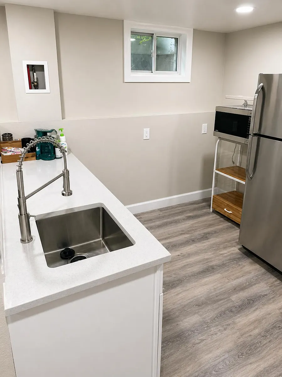 Clean, functional kitchen with quartz-style counters, deep sink and pull-down faucet, plus stainless fridge and prep space. - Lamar St
