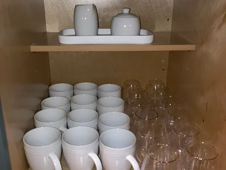 Sleek crystal glasses, mugs, and sugar accessories for guest use.