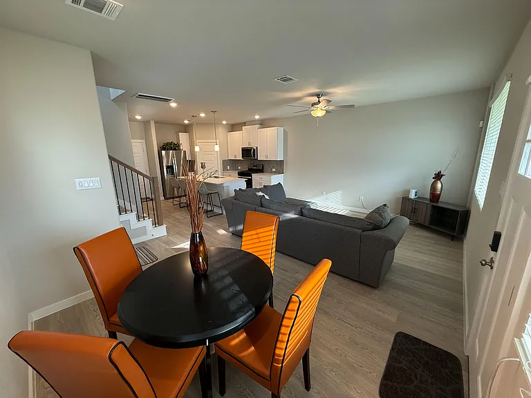 Open-concept living area with adjacent dining space and a kitchen featuring an island, bar seating, and stainless appliances.