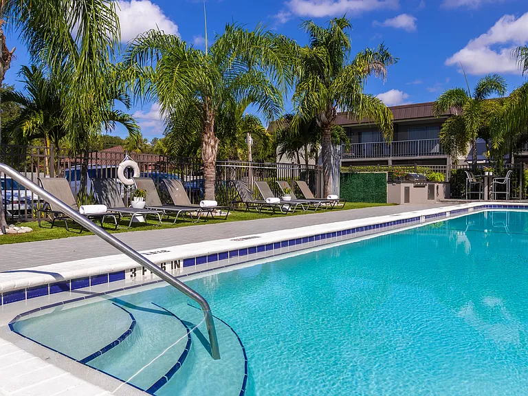 Enjoy the Florida sunshine in style at our sparkling swimming pool featuring loungers, comfortable seating, and an outdoor kitchen with gas grill.