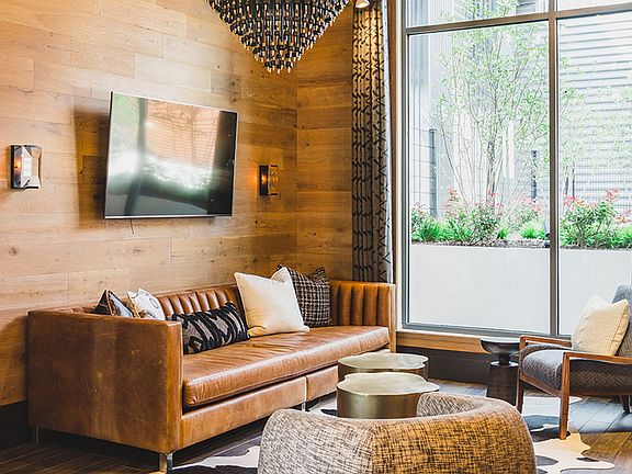 Living room setting in The Ivy Lounge with wall mounted TV and floor to ceiling windows